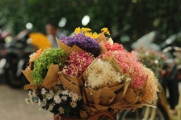 Beautiful bouquets of colorful flowers fill a bicycle basket on a sunny day.