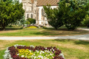 Stunning view of a gothic cathedral surrounded by a vibrant floral garden in a summer park.